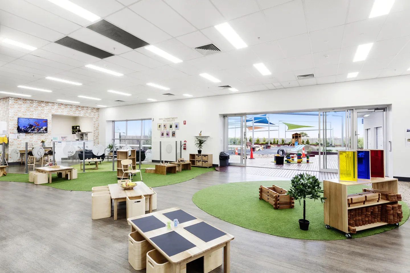 Bright early learning classroom featuring natural timber furniture, open learning zones, indoor-outdoor access, and custom play areas that encourage exploration, creativity, and collaborative learning.