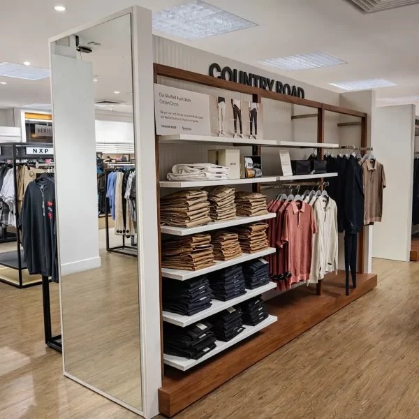 Contemporary clothing store interior with custom timber display fixtures, shelving, hanging rails and neatly arranged apparel.