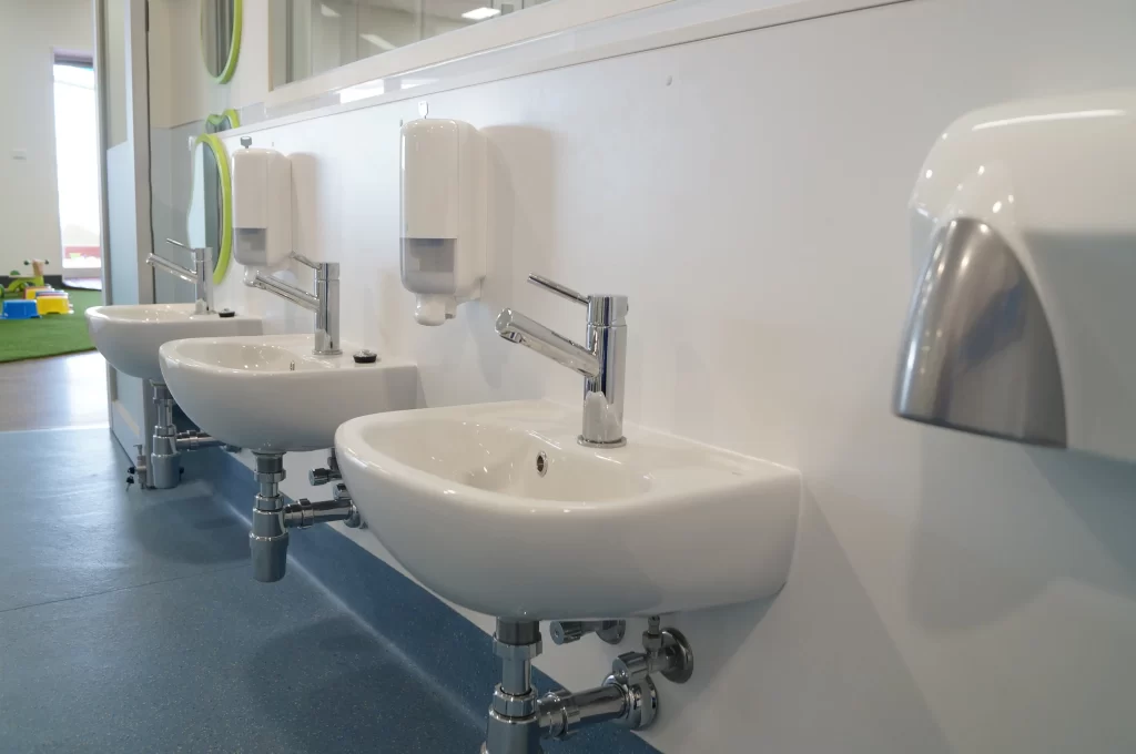 Modern childcare centre washroom featuring child-height wall-mounted hand basins, touch-free soap dispensers, and a clean, accessible hygiene area.