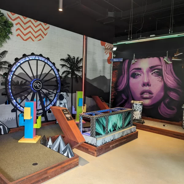 Indoor mini golf course at X-Golf Southbank with colourful obstacles and street art mural.