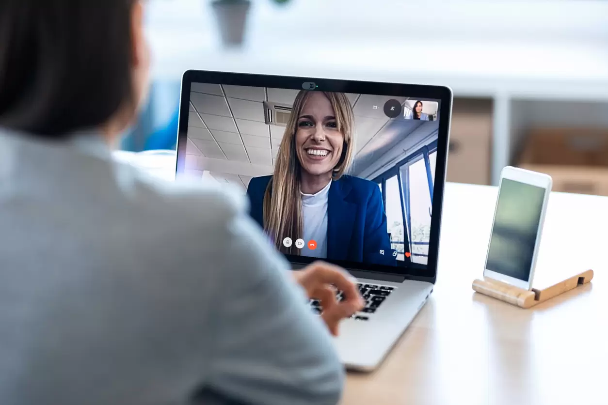 Commercial interior designer conducting a virtual video consultation with a client using a laptop, discussing commercial fit-out and interior design projects remotely.